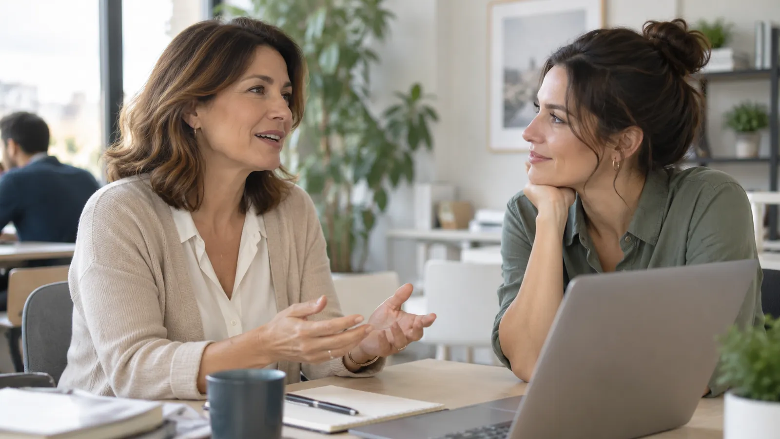 Dos mujeres adultas conversan en un espacio de trabajo tranquilo.